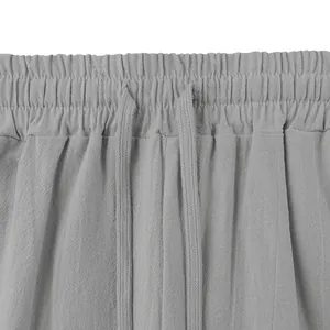Close-up view of the elastic waistband and drawstring on these grey linen pants.
