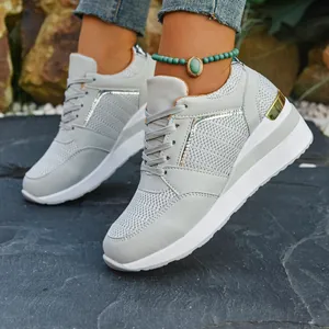 Close-up of gray platform wedge sneakers showing mesh texture and golden heel detail