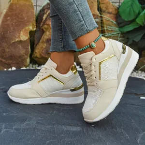 Detailed side view of cream wedge sneakers featuring gold accents on natural rock