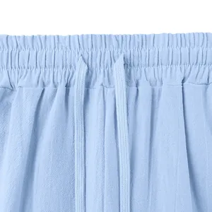 Close-up view of the elastic waistband and adjustable drawstring on light blue linen pants