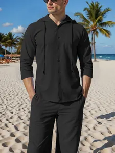 Detail view of men's black linen hooded shirt and trousers set on a sunny beach