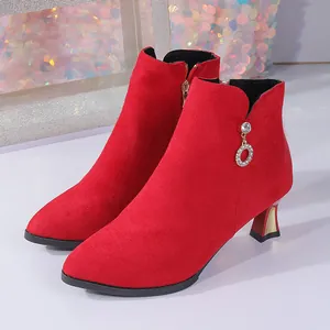 Nahaufnahme von eleganten roten Wildleder-Stiefeletten mit glitzerndem Strass-Anhänger