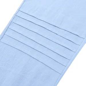 Close-up detail of light blue linen pants showing horizontal pleated design and fabric texture