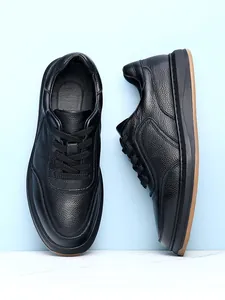 Detail view of black textured leather men's casual shoes on light blue background