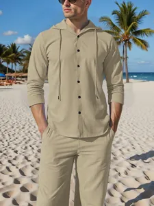 Caucasian model wears men's beige loose linen hooded shirt and pants set on a sunny beach