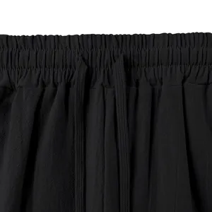 Detailed view of the elastic waistband and drawstring on these black linen wide-leg pants.