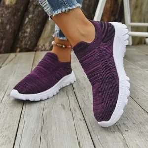 Detail view of purple breathable fly-knit slip-on sneakers on a wooden deck.