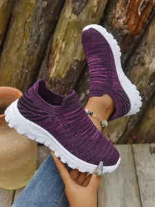 Close-up of purple breathable flyknit slip-on sneakers with thick white soles