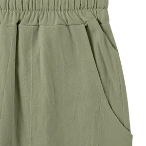 Close-up view showing the elastic waistband and side pocket details of green linen pants