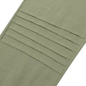 Detail shot of green linen trousers showing horizontal pleated design and fabric texture