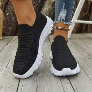 Close-up of breathable black fly-knit slip-on sneakers with durable chunky white soles.