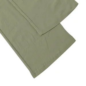 Detailed macro view of the stitched hem and linen fabric texture of green trousers