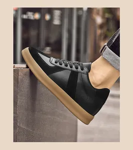Detailopname van zwarte leren GAT-sneakers met bruine rubberen zool op straat gedragen.
