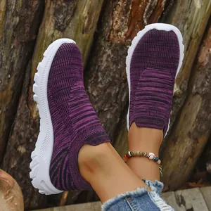 Close-up showing the texture of purple breathable fly-knit slip-on sneakers on feet