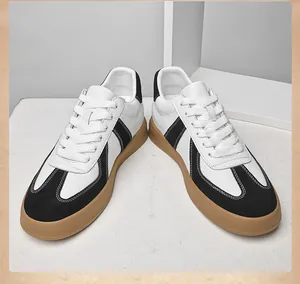 Paar retro German Army Trainers met zwart-witte lederen panelen en een bruine rubberen zool