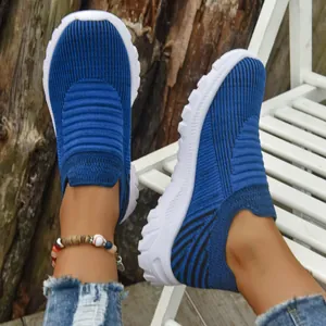 Detailed macro view of blue breathable fly-knit slip-on sneakers worn in a lifestyle setting.