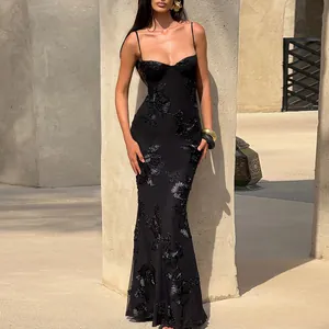 Detail of an elegant black maxi dress with 3D floral embroidery in a sun-drenched setting