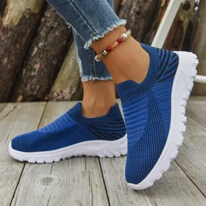 Detail view of blue breathable knit slip-on sneakers on a wooden deck background.