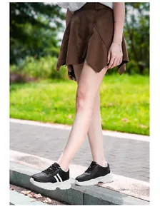 Gros plan de baskets noires respirantes avec des semelles compensées blanches de 8 cm