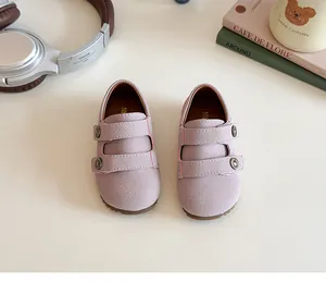 Top-down view of mauve suede baby walking shoes with double straps on a cream surface