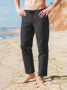 Detalle de pantalones de playa de lino para hombre con cordón en la cintura sobre arena
