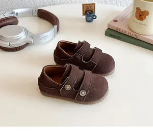 Close-up of brown suede children's walking shoes with dual velcro straps in a cozy setting