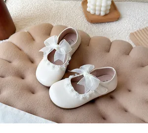 Detailed view of white girls' princess shoes featuring lace bow and delicate pearl trim