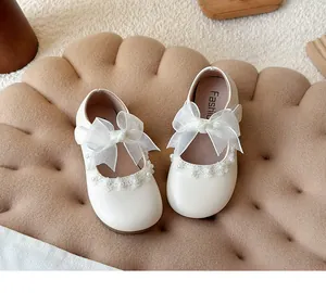Top view of white children's princess shoes with large tulle bows and pearl details
