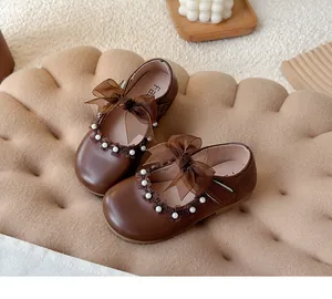 Detailed macro view of brown girls' princess shoes featuring pearls and a mesh bow