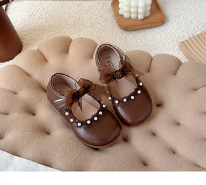 Close-up of brown girl's Mary Jane shoes with ribbon bows and pearls decoration