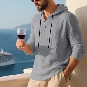 Men's grey linen hooded Henley long-sleeve t-shirt shown in a coastal vacation setting.