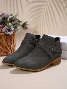 Detailansicht grauer Stiefeletten mit spitzer Zehenpartie, Seitenreißverschluss und Schnalle.