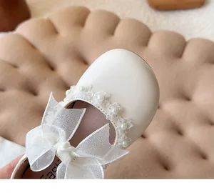 Detailed view of white girls' princess shoe with a sheer ribbon bow and pearl lace trim