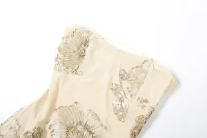 Macro detail of champagne mesh dress featuring elegant 3D floral ribbon embroidery appliqué.