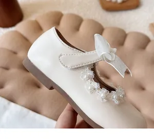 Close-up of white girls' princess shoe with pearl lace trim and sparkly bow detail