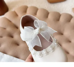 Detailed macro shot of white girl's princess shoe with large bow and pearl trim