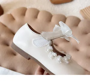 Detailed macro view of cream girls' Mary Jane shoe featuring ribbon bow and pearl lace trim