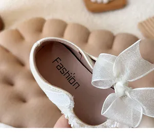 Detail of white girls princess shoe featuring a sheer bow and delicate pearl trim accents.