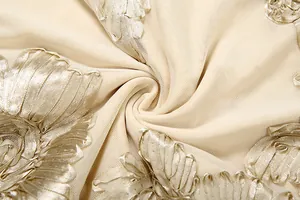 Macro view of beige tulle fabric featuring intricate champagne floral ribbon embroidery
