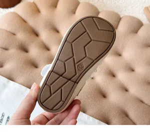 Detail view of the soft brown rubber sole of a girl's white leather shoe