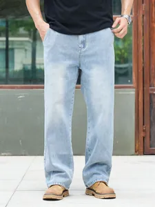 Full-length view of premium men's loose straight-leg jeans in light blue wash denim.
