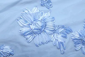 Macro view of intricate blue three-dimensional ribbon floral embroidery on mesh fabric