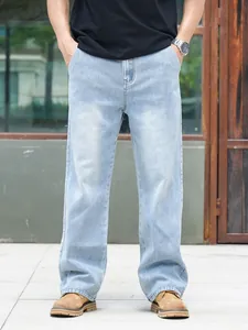 Detail view of men's loose straight-leg light blue denim jeans in outdoor setting
