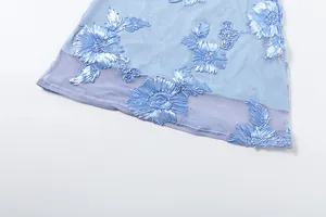 Macro view of blue floral embroidery on light mesh fabric for this summer maxi dress.