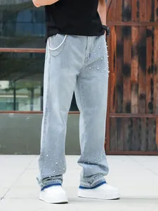 Detail view of men's loose straight-leg jeans with decorative pearl beading and metal chains.