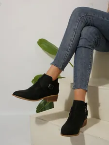 Side view of black pointed toe ankle boots with square heel and metal buckle strap detail