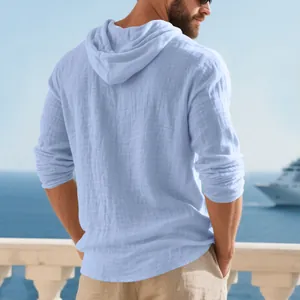 Back view of men's breathable light blue linen hooded T-shirt against a seaside cruise background.