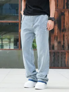 Detailed view of men's straight-leg light blue denim jeans with pearl bead embellishments.