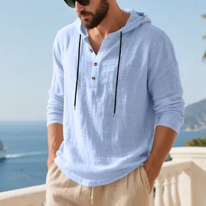Detail shot of men's light blue linen hooded Henley shirt with buttons in a sunny seaside setting