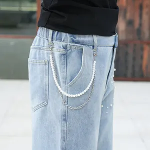 Detail view of light blue jeans with pearl chain and rhinestone embellishments